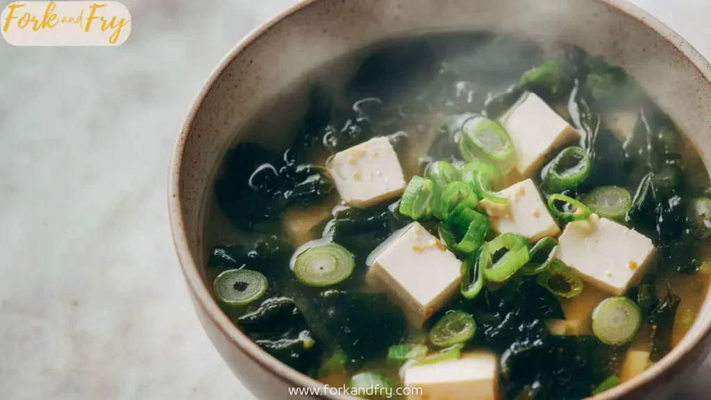 Close-up of classic Japanese miso soup with tofu cubes and seaweed in white bowl