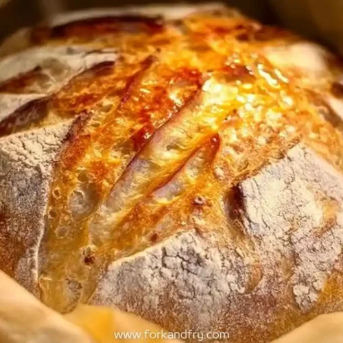 golden sourdough bread with crusty top and deep score marks on parchment paper