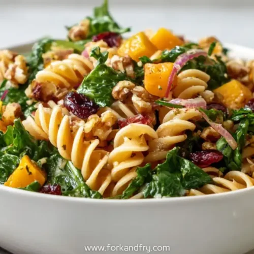 bowl of rotini pasta salad with kale, roasted butternut squash, walnuts, cranberries and red onions