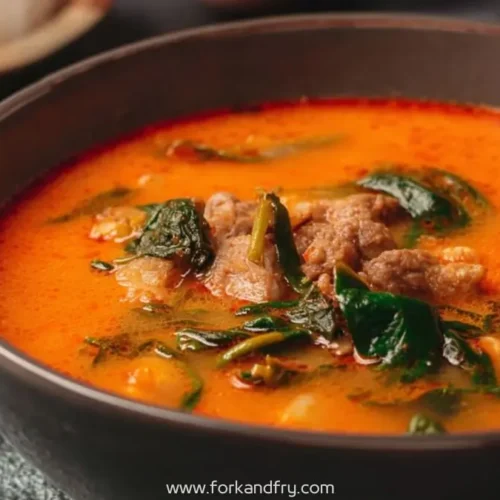 hearty beef and spinach soup in orange broth served in a black bowl with Fork and Fry branding