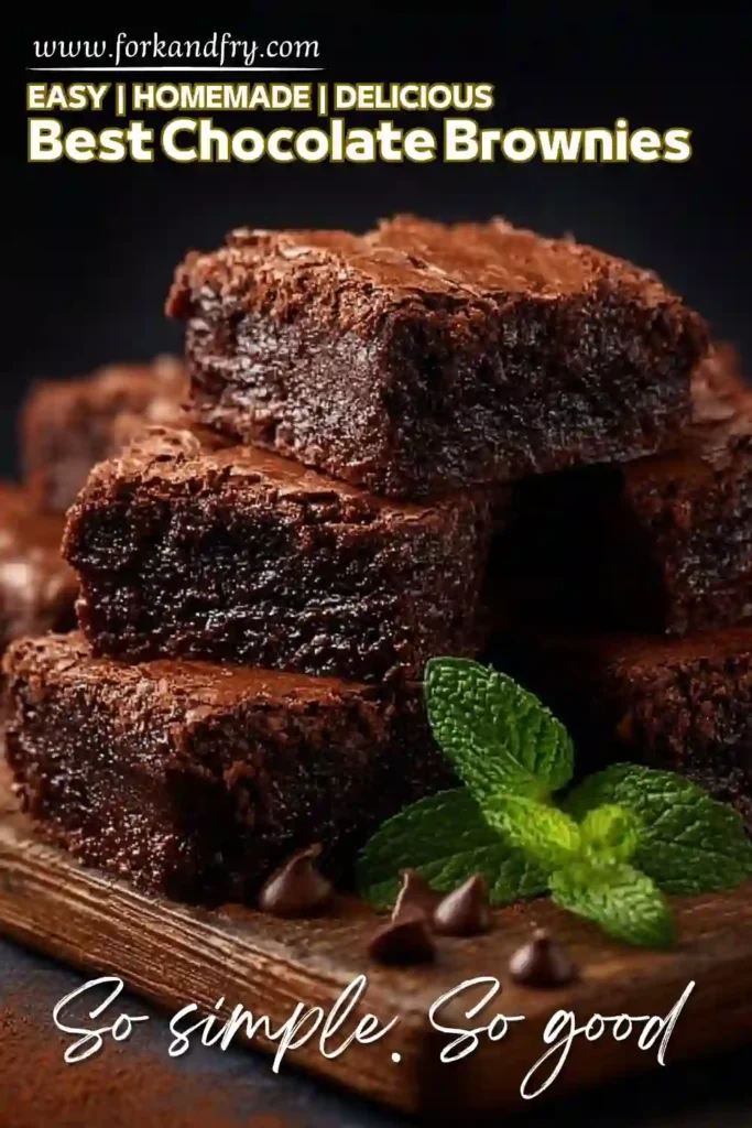 stacked fudgy chocolate brownies on a wooden board with mint and chocolate chips
