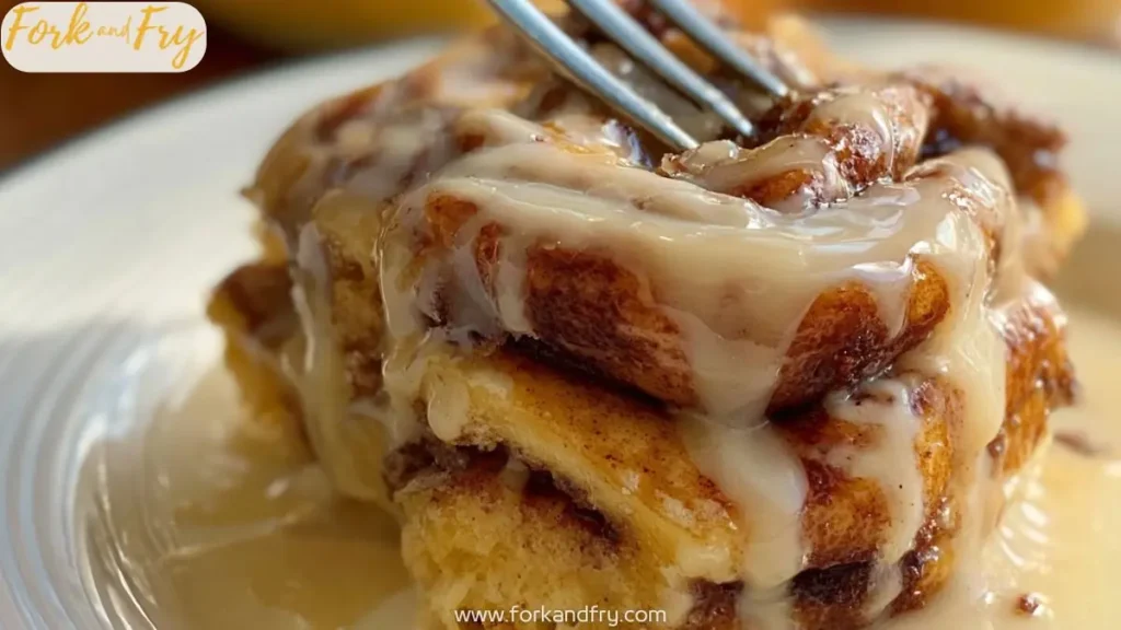 gooey cinnamon roll topped with creamy vanilla glaze and fork about to slice