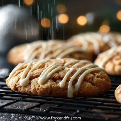 Maple brown sugar cookies with white icing drizzle on cooling rack, with holiday lights in background