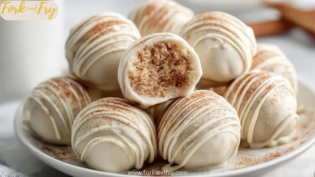 White chocolate cookie truffles stacked on plate with cinnamon and drizzle detail and bite showing inside texture